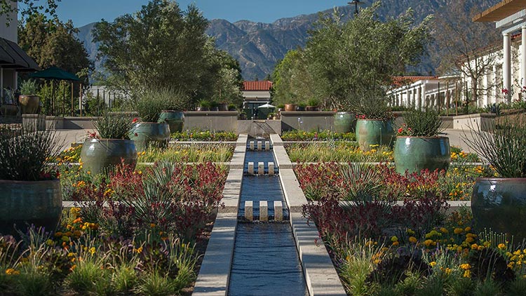 Front view of Huntington Library with grand steps, columns, and manicured gardens.